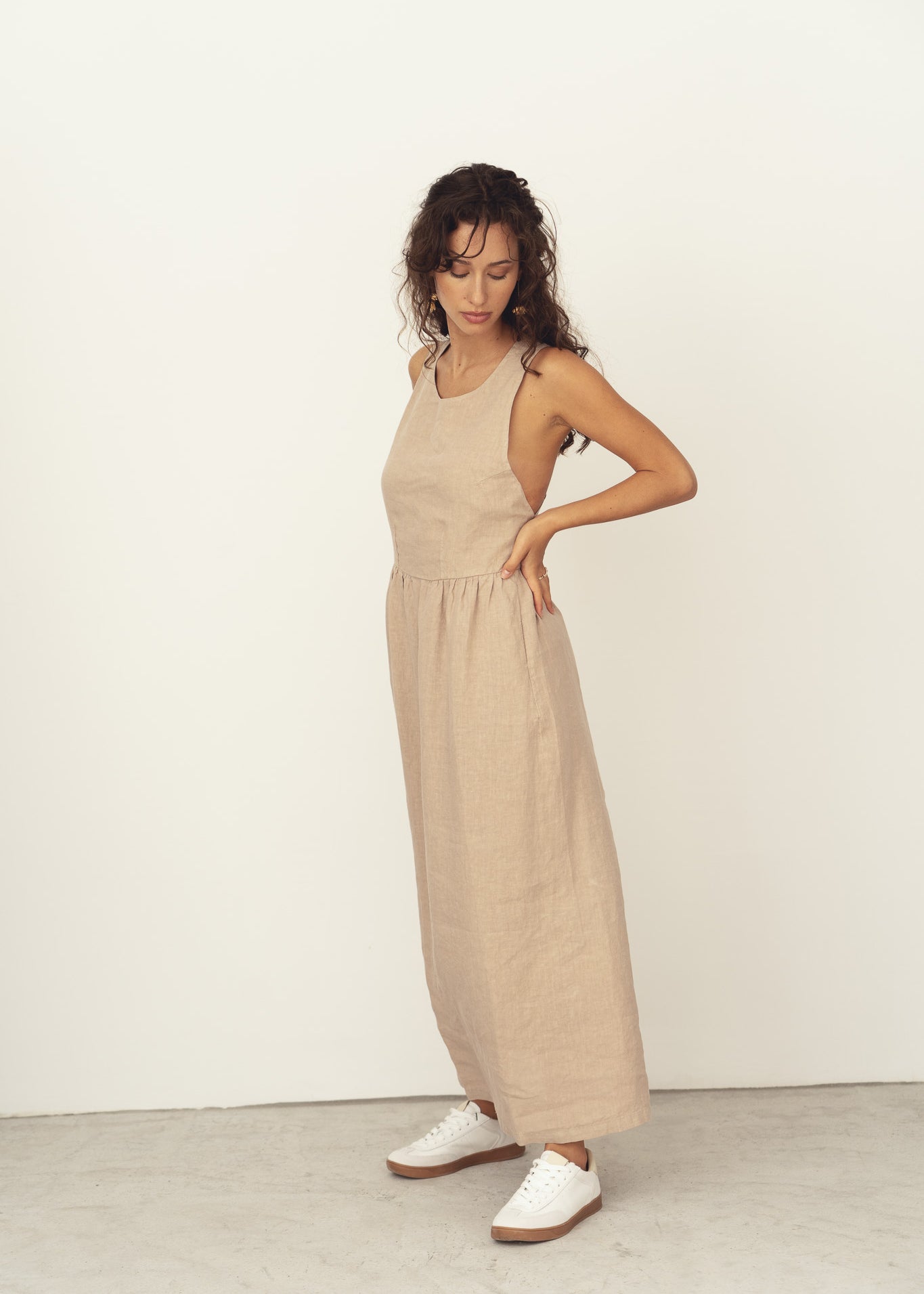 Naz women's sustainable linen dress in beige. Features a halter neck crossed strap back and side pockets. Ethically produced in Portugal. 